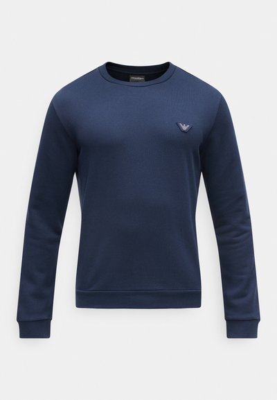 Μακρυμάνικη μπλούζα σε ναυτικό μπλε με στρογγυλή λαιμόκοψη και μικρό τρίγωνο λογότυπο στο αριστερό στήθος, με ριμπ μανσέτες και τελείωμα.