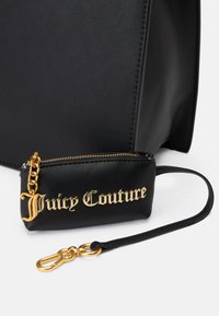 Melns mākslīgās ādas rokdarbs ar noņemamu mazu somiņu. Zelta detaļas un "Juicy Couture" logo uz somiņas ar izteiksmīgu fontu.