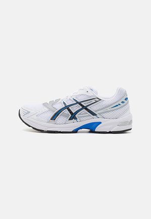 Chaussure de sport blanche avec tige en mesh et synthétique, accents argent et bleu, semelle rembourrée et design à bout arrondi.