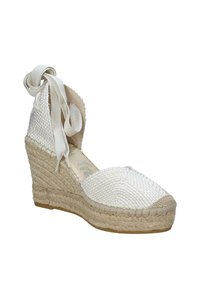 Scarpa espadrilla a zeppa in tessuto bianco intrecciato con suola in corda di juta, caratterizzata da un nastro avvolgente alla caviglia e design a punta arrotondata.