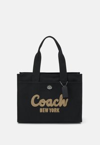 Juodas kanvos tote krepšys su dekoratyviu auksiniu siuvinėjimu "Coach New York" logotipo, dviem rankenomis ir metaline uždarymo detale.