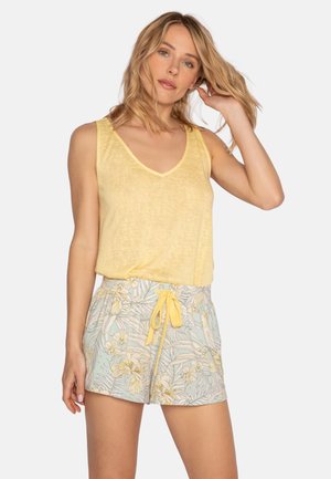 Haut sans manches jaune avec un col en V associé à un short bleu clair à motif floral et taille avec cordon de serrage.