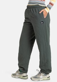 Groene gewatteerde broek met een elastische tailleband en zijzakken, voorzien van een zwart logo label. Gestyled met grijze sneakers.