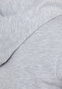 Light grey hoodie with a soft, textured fabric. It features a smooth design and subtle tonal variations throughout the material.