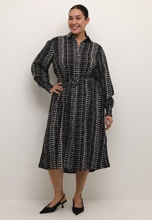 Zwart-wit gestreepte jurk met een kraag, lange mouwen en een getailleerde taille, gemaakt van een soepele, vloeiende stof.