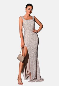 Pailletten jurk in champagnetint, aangesloten silhouet met vierkante halslijn, splitdetail, gecombineerd met een bejeweled handtas en sandaaltjes met bandjes.