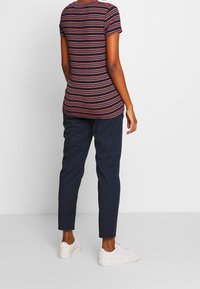 Czarna, czerwona i biała, pasiaste dopasowane t-shirt, w połączeniu z granatowymi, zwężającymi się spodniami. Białe trampki dopełniają look. Teksturowany, casualowy design.