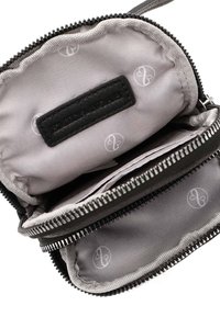 Schwarze Lederbörse mit silbernem Reißverschluss, ausgestattet mit einem grauen Stoffinnenfutter mit Logo-Muster und Ausschnitten entlang der Kanten.