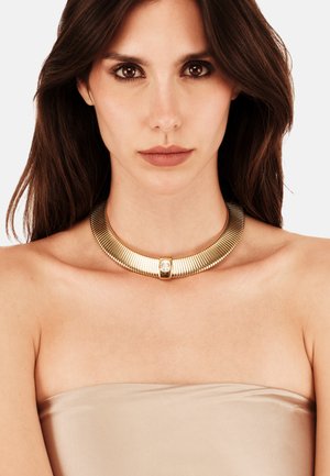 Guld chokersmykke med et ribbet design, glat central accent og en reflekterende overflade. Egnet til formelt eller afslappet brug.