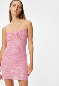 Trägerloses pinkes Kleid mit einem Twist-Design an der Brust, mit Pailletten bedeckt, figurbetonte Silhouette und kurzem Saum.