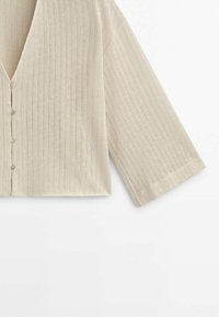 Beige gebreide cardigan met geribbelde textuur, V-hals, sluiting met knopen aan de voorkant en driekwart mouwen. Eenvoudig ontwerp zonder extra patronen.