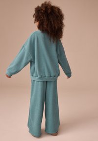 Türkisfarbener, gerippter Lounge-Set mit locker sitzendem Langarmshirt und weitem Hosenbein, aus strukturiertem Stoff mit lässiger Silhouette.