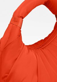 Borsa a tracolla arancione imbottita con una texture liscia, caratterizzata da un manico arrotondato e un delicato dettaglio di cucitura. Chiusura con zip lungo il bordo superiore.