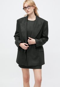 Sacou tailored de un gri închis, cu o siluetă structurată, design dublu-botoș și umeri, asortat cu o rochie fitted de aceleași culori.