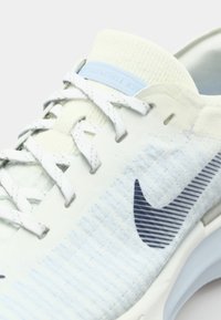 Light blue running shoe featuring a textured knit upper, white laces, and a navy Nike swoosh. Cushioned sole with a sleek design.