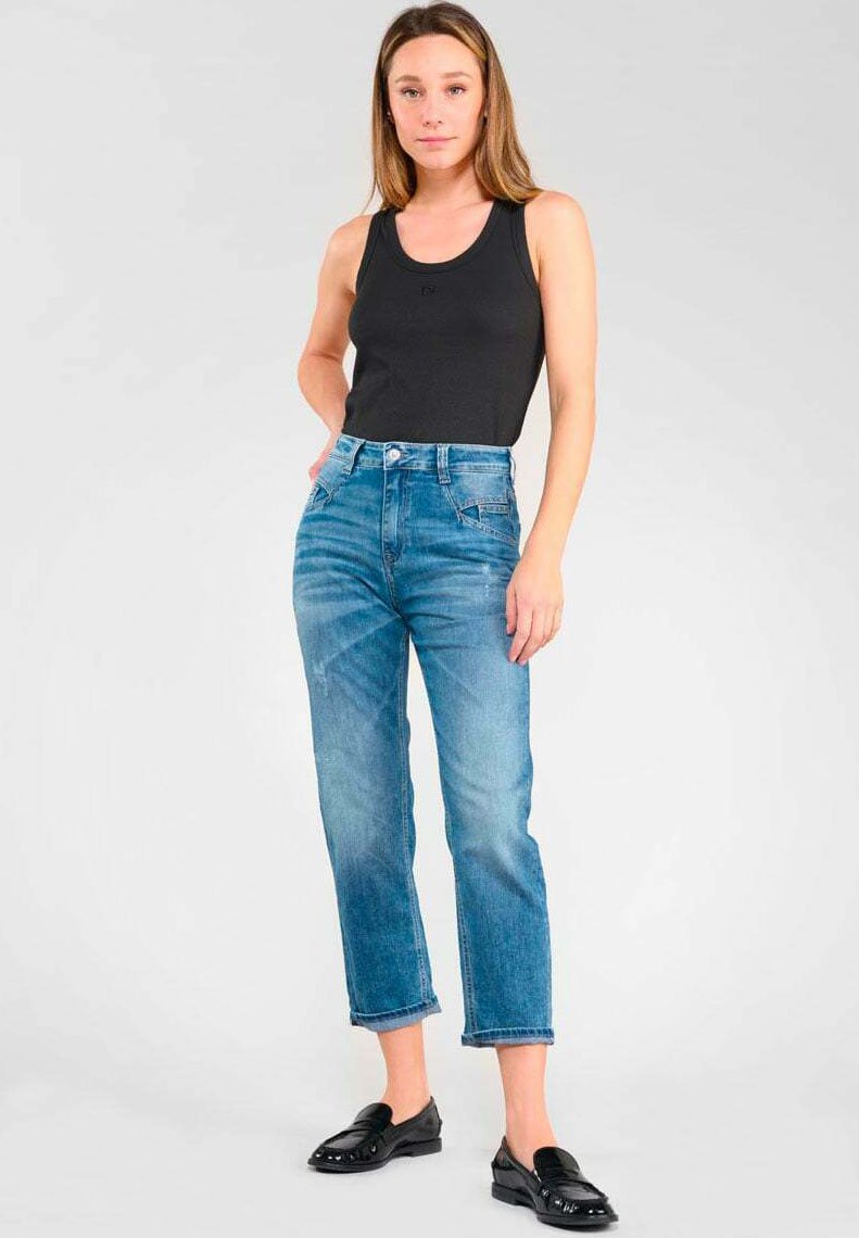 Jean taille haute en denim bleu clair avec une coupe droite, associée à un débardeur noir et des mocassins noirs. Texture lisse, design classique.