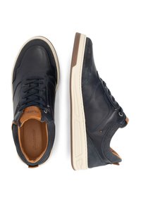 Navy leren en suède sneakers met witte en lichtbruine zolen. Kenmerken zijn onder andere veters, contrasterende materialen en subtiele branding op de binnenzool.