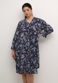 Vestido azul marino con un estampado de paisley en varios colores, mangas largas con puños elásticos y escote en V. Tejido ligero.