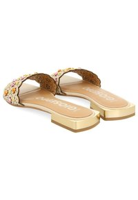 Sandalias planas de punta abierta en beige con bordes festoneados, decoradas con tachuelas multicolores. Los tacones de bloque en color dorado realzan el diseño.