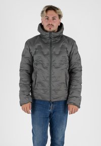 Gevoerde jas in donkergrijs met een hoge kraag en ritssluiting. Heeft een gestructureerde buitenkant en lange mouwen. Gemaakt over een blauwe jeans.