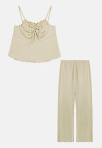 Camiseta sin mangas color beige claro con tirantes ajustables, que presenta un escote fruncido, combinada con pantalones holgados a juego. Tejido suave y texturizado.