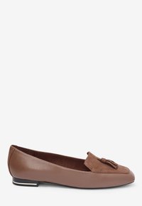 Mocassin plat en cuir marron avec détail de pompon en daim et talon noir avec une bande argentée, présenté de profil sur fond blanc.