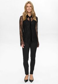 Mustmustest mustriga pikad varrukad ja krae, nupuvajutusega esiosa ja keerukad lillemustrid. Kombineeritud mustade sobivate pükstega.