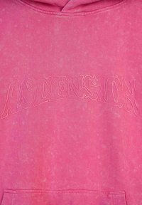 Różowa bluza z kapturem o miękkiej, teksturowanej tkaninie, z napisem "ASCENSION" w nieco ciemniejszej, konturowej czcionce na klatce piersiowej.