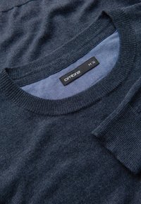 Maglione lavorato a maglia blu navy con collo rotondo, morbida consistenza e polsini a coste. Etichetta visibile con il nome del brand "ombré" e taglia "M".