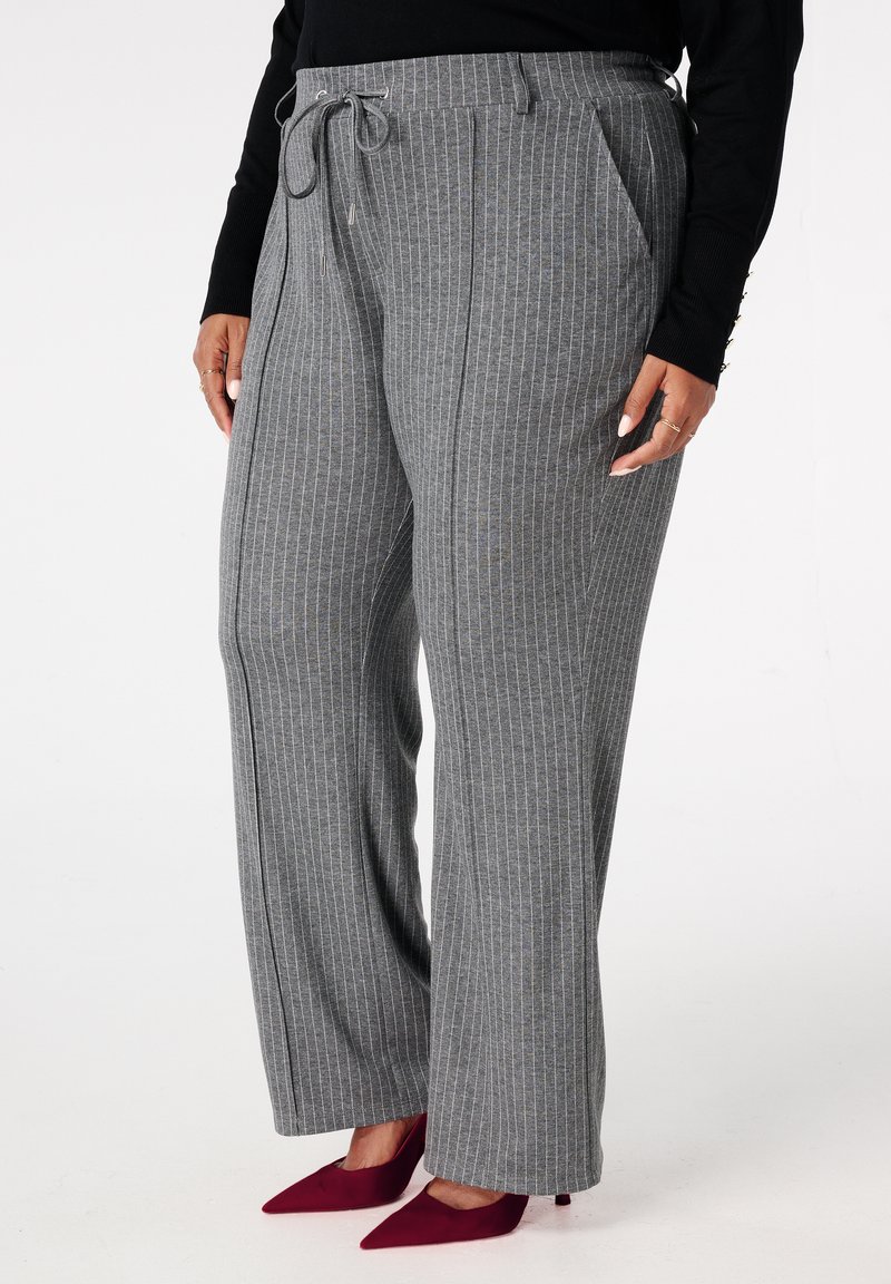 Grijze pantalon met krijtstrepen, gemaakt van zachte stof met een losse pasvorm, voorzien van zijzakken en een trekkoord in de taille. Gecombineerd met bordeauxrode hakken.