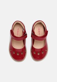 Scarpe Mary Jane in pelle verniciata rossa con cinturino, dettagli intagliati e fodera interna beige. Suola in gomma con bordatura cucita.