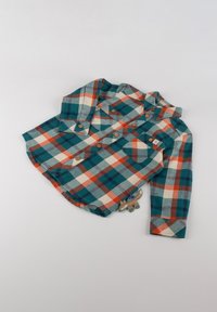 Camicia di flanella con motivo a quadri nei colori turchese, arancione e crema. Presenta chiusure a bottone, due tasche sul petto e un ciondolo decorativo a forma di volpe.