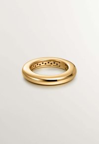 Anillo de oro con un exterior suave y redondeado y un centro hueco. Presenta recortes espaciados uniformemente a lo largo de la banda interior como detalle de diseño.