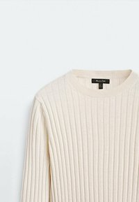 Pull en maille côtelée de couleur crème avec col rond et manches longues, posé à plat sur un fond blanc.