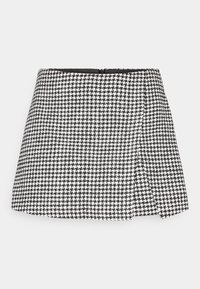 Jupe en pied-de-poule noir et blanc avec un design évasé, en tissu texturé, et une fermeture éclair dissimulée à l'arrière.