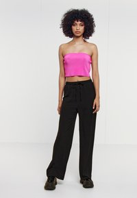 Pantaloni neri a gamba larga con vita regolabile, abbinati a un crop top senza spalline di colore rosa shocking con texture a coste. Tessuto morbido, design casual.