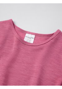 Vaaleanpunainen lyhythihainen paita, jossa on pyöreä pääntie. Pehmeä kangas ja kevyt materiaali. Tagi näkyvissä brändin ja koon tiedoilla.