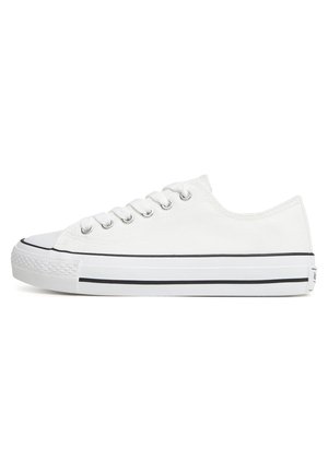 Biały tenisówka na płótnie z gumowym noskiem, metalowymi przelotkami i czarnymi paskami na podeszwie. Płaskie sznurowadła i niska konstrukcja.