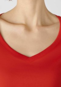 Rode V-hals top met een soepele textuur en korte mouwen; de halslijn heeft een nette stiksel detail. Geschikt voor casual kleding.