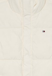 Kremfarget puffjakke med horisontal quilting og liten Tommy Hilfiger-logo på venstre brystside.