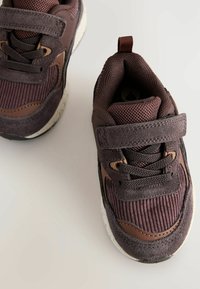 Brune atletiske sko med en blanding af suede og mesh materialer, med en tekstureret overflade, Velcro-rem og mønstret gummisål.