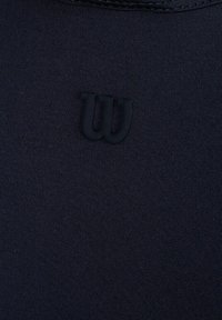 Camiseta deportiva negra con un tejido texturizado. El diseño incluye un sutil logo "Wilson" en tono sobre tono en la zona del pecho.