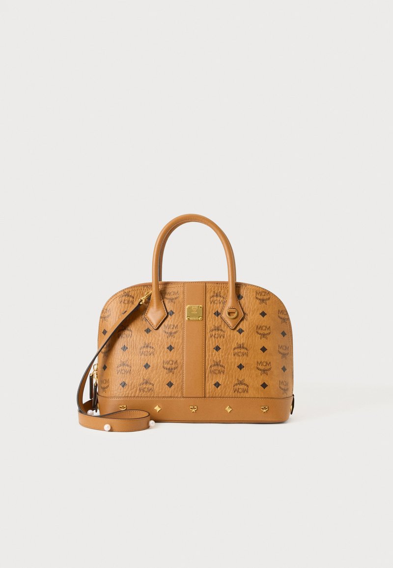 Sac à main en cuir beige avec motif logo MCM, finitions dorées, deux poignées et une bandoulière réglable sur fond blanc uni.