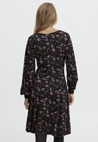 Langärmliges Kleid aus schwarzem Stoff mit buntem Blumenmuster. Ausgestellter Rock und runder Ausschnitt. Weicher Griff, leicht elastisch.