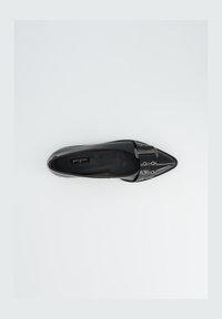 Zwarte leren platte schoen met een spitse neus, zilveren gespaccent en kleine ronde uitsparingen op de band. Gladde textuur en minimalistisch ontwerp.