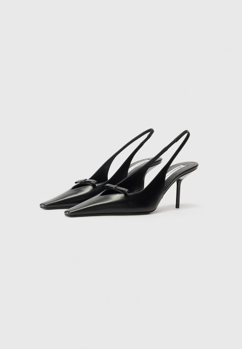 Sorte læder slingback hæle med spids tå, lille dekorativ sløjfe foran og en tynd stiletto hæl. Glat tekstur, minimalistisk design.