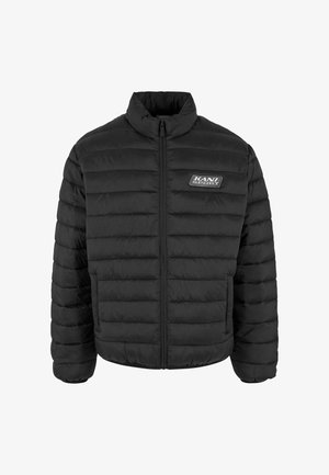 Veste matelassée noire avec un col haut, présentant un rembourrage segmenté, une fermeture éclair à l'avant et un logo KANI SPORT sur la poitrine gauche.