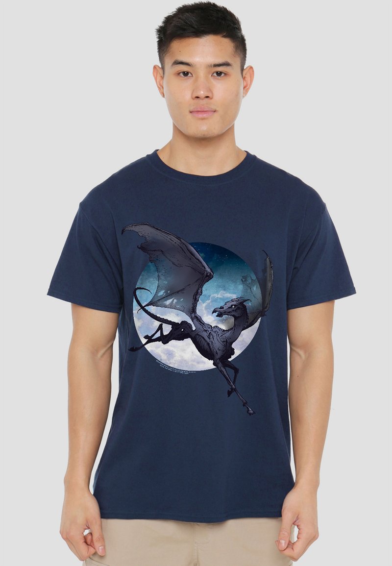 Young man wearing a navy blue T-shirt with a graphic of a black dragon flying in front of a moonlit sky circle.