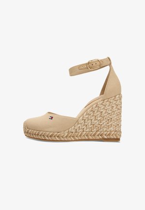 Beige canvas sleehak espadrille met gevlochten jute plateau, enkelriem met gouden gesp en klein rood, wit en blauw logo op de teen.