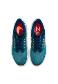 Tyrkysové sportovní boty s texturovaným svrškem, modrými tkaničkami a růžovými akcenty; mají odpruženou podrážku a vzorovaný design na povrchu.